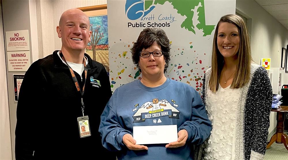  Image of JG's Pub owner presenting a donation to school administration for the Cool Schools Dunk.