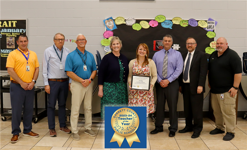 Mrs. Schilpp holds a recognition certificate with other GCPS staff and GCBOE members surrounding her.